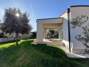 a small white building with a table in a yard at Holiday Home Aurora in Ližnjan