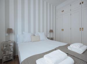1 dormitorio con 1 cama blanca grande y toallas. en Bright Apartment in the Heart of Seville, en Sevilla