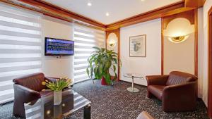 a living room with two chairs and a tv in a room at Hotel am Schelztor in Esslingen