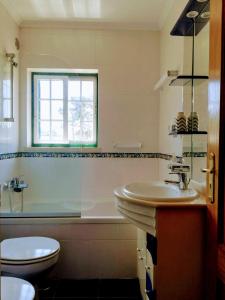 a bathroom with a sink and a tub and a toilet at TripGeo Pinhal da Aroeira Villa in Almada
