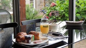 ein Tablett mit einem Glas Orangensaft und Brot auf dem Tisch in der Unterkunft Citotel Les Sternes in Perros-Guirec