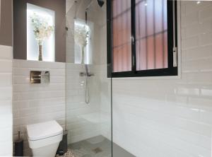a bathroom with a toilet and a glass shower at Arjona Suite Apartment in Seville