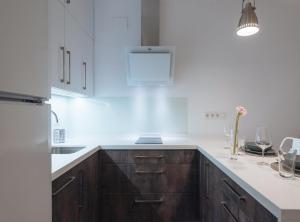 uma cozinha com armários de madeira e bancadas brancas em Arjona Suite Apartment em Sevilha