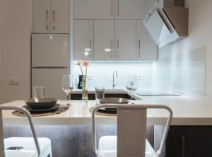 una cucina con armadi bianchi e un tavolo con bicchieri di Luxury Apartment in Plaza de Armas a Siviglia