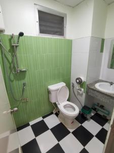 a green bathroom with a toilet and a sink at UJ apartment in Bangsaen