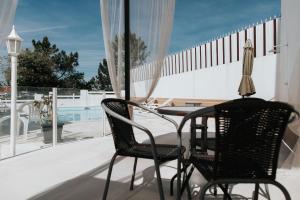 a patio with two chairs and a table on a balcony at Beach House Outeirinho in Ericeira