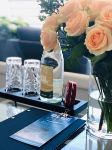 einen Tisch mit einer Flasche Wein und einer Vase Rosen in der Unterkunft Blue City Apartments in Lübeck
