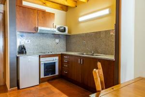 een keuken met houten kasten en een wastafel bij Apartaments Sant Moritz in Arinsal