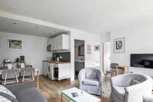 uma sala de estar com um sofá e cadeiras e uma cozinha em Sunny & quiet 2br near the Eiffel Tower Invalides Beaugrenelle Welkeys em Paris