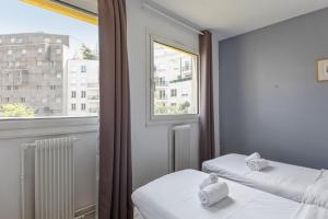two beds in a room with a window at Sunny & quiet 2br near the Eiffel Tower Invalides Beaugrenelle Welkeys in Paris