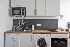 eine Küche mit weißen Schränken und einer Waschmaschine in der Unterkunft Appartement de la Motte - Welkeys in Paris