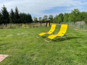 two yellow chairs sitting in the grass in a field at Sol Panzió in Bük