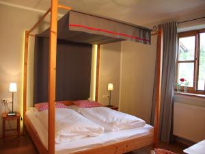 a bedroom with a canopy bed with white sheets and red pillows at Seeleitenhof in Sindelsdorf