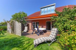 ein Haus mit einer Terrasse mit 2 Stühlen und einem Tisch in der Unterkunft Jever-Ferienhaus Gartenblick in Jever
