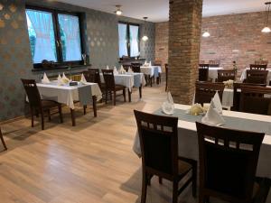 a dining room with white tables and chairs and windows at A&P Motel in Mikołów