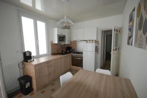 a kitchen with a wooden table and a white refrigerator at La réserve à bonheurs in Les Sables-d'Olonne