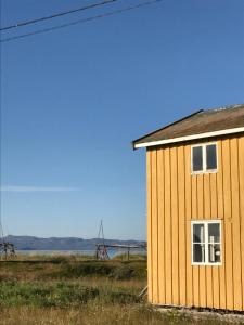 a yellow building in a field next to the ocean at Jakobselvkaia in Vadsø