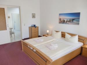 - une chambre avec un grand lit et des draps blancs dans l'établissement Haus Feldmann, à Ahlbeck