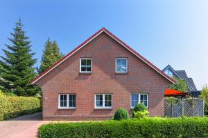 een rood bakstenen huis met witte ramen en struiken bij Jever-Ferienhaus Himmelsblick in Jever