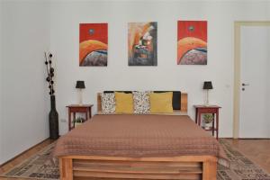 a bedroom with a bed and some paintings on the wall at Paprika Apartment Grand in Budapest