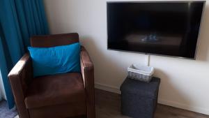 uma cadeira com uma almofada azul e uma televisão de ecrã plano em De Sprink - Vakantiewoning em Zoutelande