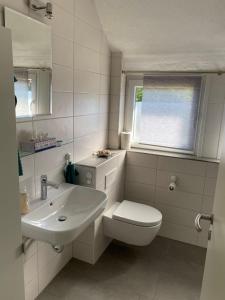 uma casa de banho com um lavatório, um WC e uma janela. em Ferienwohnungen Thingslinde em Kierspe