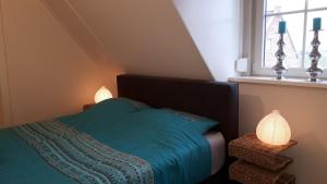 - une chambre avec un lit doté d'une couverture bleue et d'une fenêtre dans l'établissement De Sprink - Vakantiewoning, à Zoutelande
