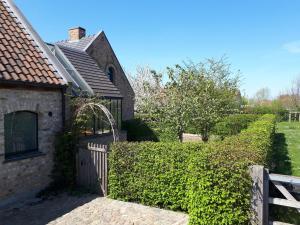 ein Haus mit einem Zaun und einer Hecke in der Unterkunft Vakantiehoeve De Klepperij in Houthulst