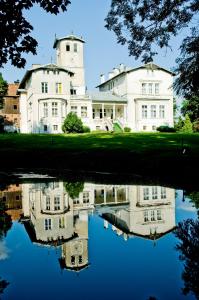 a large white house with its reflection in the water at Agroturystyka "Pałac w Janowie" in Janów