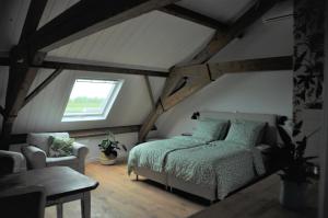 um quarto com uma cama e uma cadeira num sótão em Bed & Brood De Vogelpoel em Wijk bij Duurstede