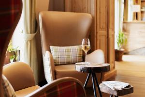a glass of wine on a table next to a chair at Hotel Ahornhof in Lindberg