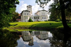 a large white house with a reflection in a pond at Agroturystyka "Pałac w Janowie" in Janów