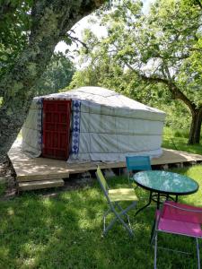 Jurte mit Tisch und Stühlen im Gras in der Unterkunft Yourte mongole véritable in Montcaret