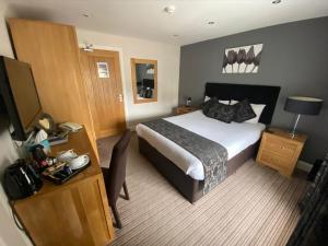 Habitación de hotel con cama, escritorio y TV. en The Three Horseshoes Hotel en Barnard Castle