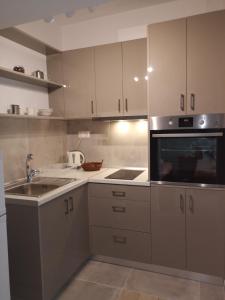a kitchen with white cabinets and a sink and a microwave at Gina Studios in Benitses