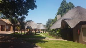 a group of cottages with thatched roofs at B at Home Guest House in Piet Retief