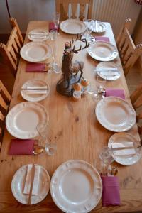een houten tafel met witte borden en wijnglazen bij Chalet Roseau in Megève