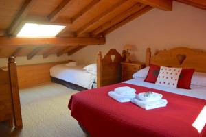 ムジェーヴにあるChalet Roseauのベッドルーム1室(ベッド2台、赤いシーツ、タオル付)