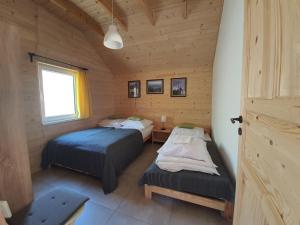een slaapkamer met 2 bedden in een houten hut bij Podbucznik 3 Leskowiec in Targoszów +65 foto's