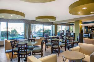 La Quinta by Wyndham Oakland Airport Coliseum في آوكلاند: مطعم بطاولات وكراسي ونوافذ
