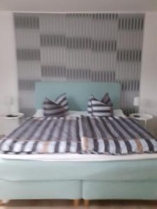 Bett mit gestreiften Kissen auf einem Zimmer in der Unterkunft Ferienwohnung Busdorf in Busdorf