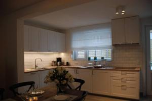 オーステンデにあるAylise vakantiehuisの白いキャビネットと花のテーブル付きのキッチンが備わります。 +5枚の写真