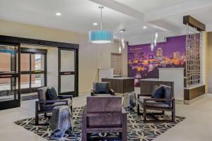 a lobby with chairs and a painting of a city at La Quinta Inn by Wyndham Columbia SE Fort Jackson in Columbia