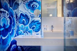 La salle de bains bleue et blanche est pourvue d'un lavabo et d'un miroir. dans l'établissement Carlton Ambassador, à La Haye