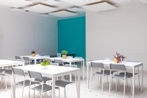 a room with white tables and chairs and a blue wall at Hostel Montessori in Gdańsk