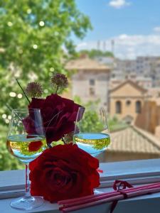 dois copos de vinho e um vaso de flores sobre uma mesa em Glory House Trastevere em Roma