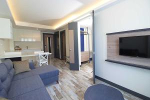 een woonkamer met een bank en een tv aan de muur bij Acropol Of Bodrum Beach Hotel in Ortakent