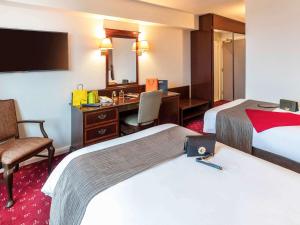 Habitación de hotel con 2 camas y escritorio en ibis London Earls Court, en Londres