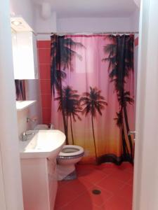 a bathroom with a shower curtain with palm trees on it at Alexandra Apartament in Sarandë