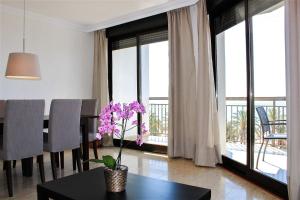 una sala de estar con una mesa con un jarrón con flores púrpuras en Port-Beach Alicante 1 en Alicante